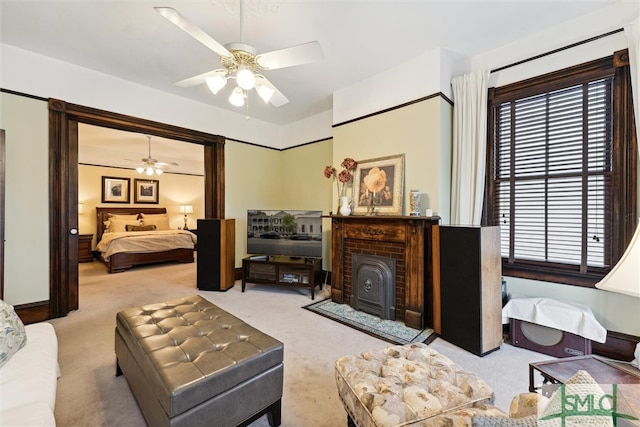 carpeted living room featuring a wood stove, ceiling fan, and a brick fireplace