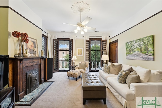 living room featuring carpet flooring, ceiling fan, and a brick fireplace