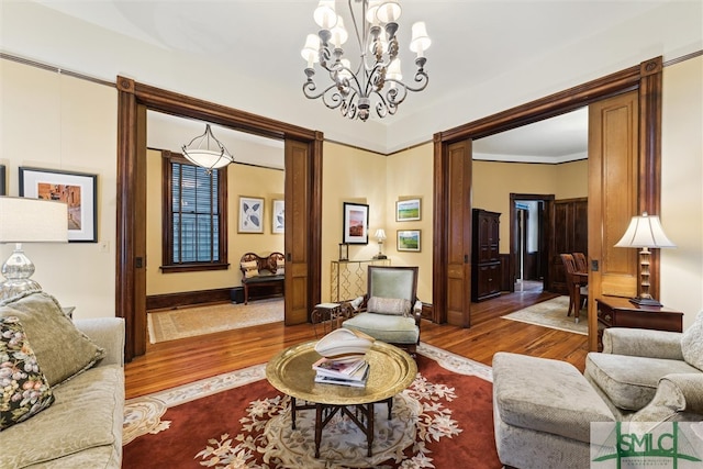 living room featuring wood-type flooring, crown molding, and a notable chandelier