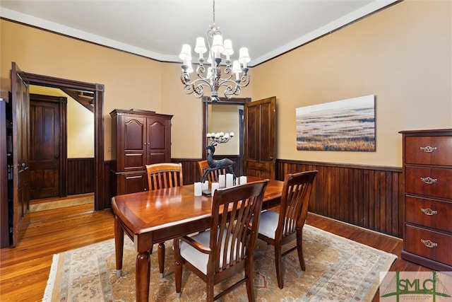 dining space with wood-type flooring, a notable chandelier, and ornamental molding