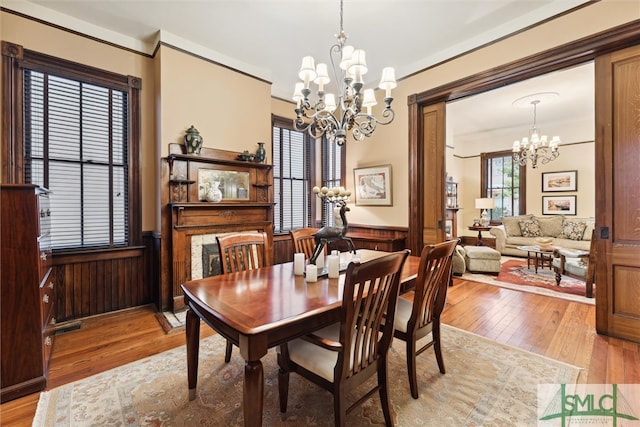 dining space featuring crown molding, wood walls, an inviting chandelier, and light wood-type flooring