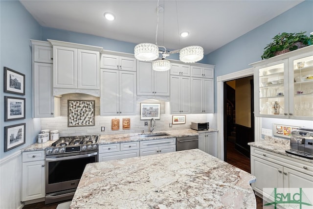 kitchen with white cabinetry, dark hardwood / wood-style flooring, sink, light stone countertops, and appliances with stainless steel finishes