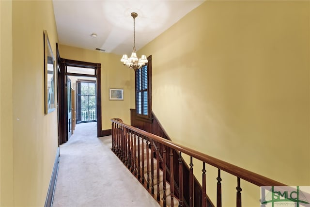 hall with a notable chandelier and light carpet