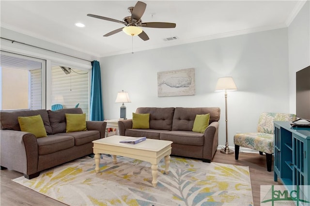 living room featuring light wood-style flooring, visible vents, and crown molding