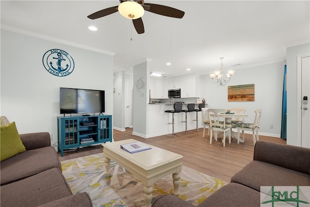 living room with ceiling fan with notable chandelier, crown molding, and hardwood / wood-style flooring