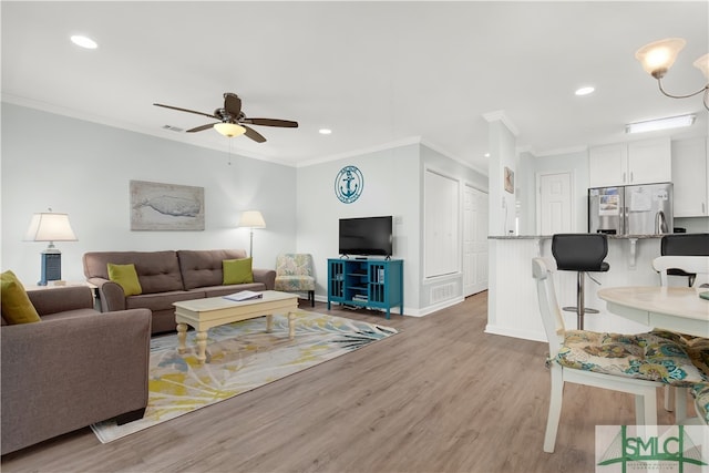 living room featuring crown molding, ceiling fan, and light hardwood / wood-style floors