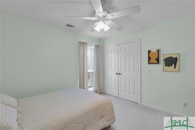 bedroom with a closet, light colored carpet, visible vents, a ceiling fan, and baseboards