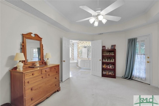 bedroom featuring access to exterior, a tray ceiling, light carpet, ceiling fan, and ensuite bath