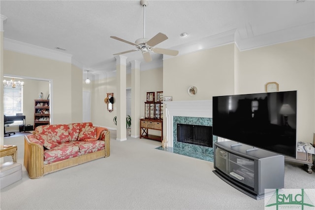 carpeted living room with crown molding, a high end fireplace, and ceiling fan with notable chandelier