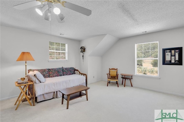 living area featuring a textured ceiling, ceiling fan, carpet, and visible vents