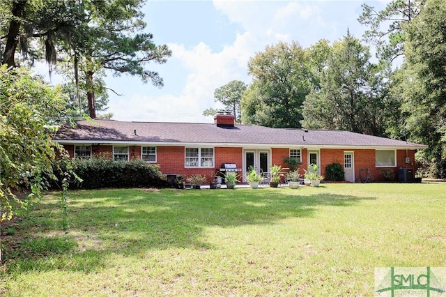 ranch-style house with central AC unit, a chimney, a front lawn, french doors, and brick siding