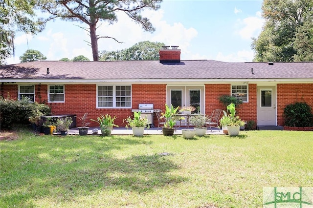 back of property with a lawn, brick siding, roof with shingles, and a chimney