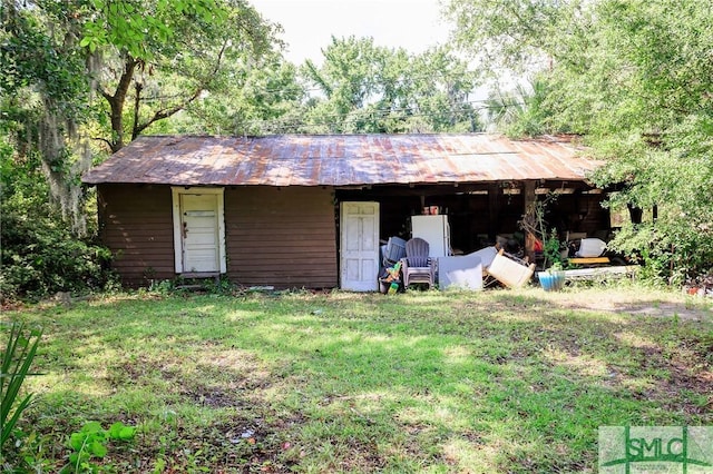 exterior space featuring a front yard, an outdoor structure, and metal roof