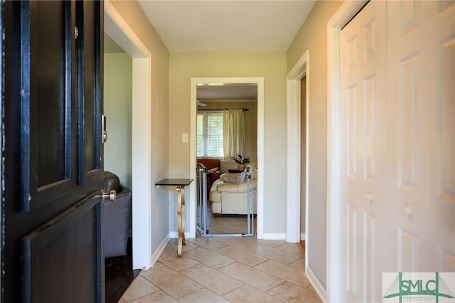 corridor featuring light tile patterned floors and baseboards