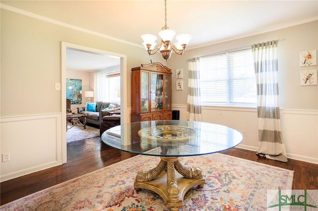 dining room with an inviting chandelier, ornamental molding, wood finished floors, and wainscoting