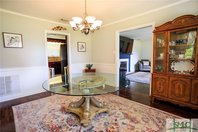 dining room featuring ornamental molding, sink, a notable chandelier, and dark hardwood / wood-style floors