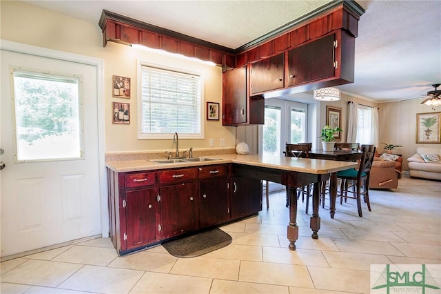 kitchen with a sink, open floor plan, light countertops, light tile patterned floors, and ceiling fan