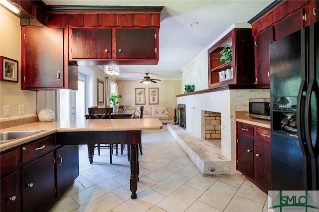 kitchen with a ceiling fan, stainless steel microwave, light countertops, a brick fireplace, and black refrigerator with ice dispenser