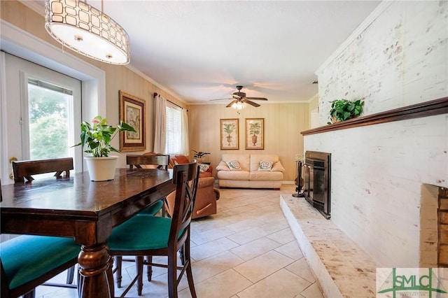 dining room featuring light tile patterned floors, a large fireplace, crown molding, and ceiling fan