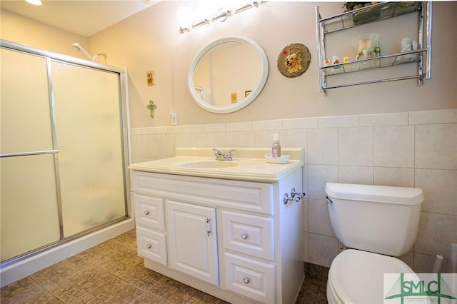 bathroom with toilet, tile walls, a stall shower, and vanity