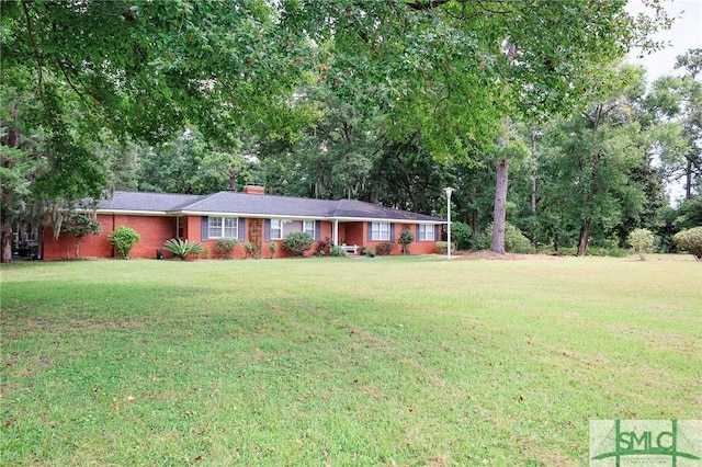 single story home with brick siding, a chimney, and a front lawn