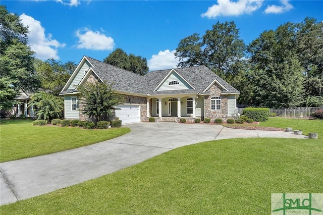 view of front of property with an attached garage, fence, stone siding, driveway, and a front lawn