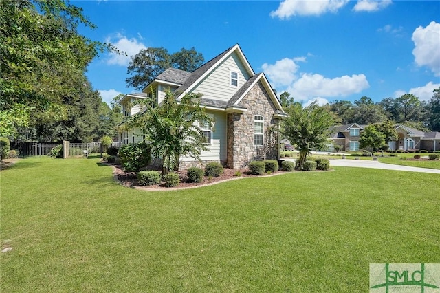 view of front facade with stone siding, a front lawn, and fence