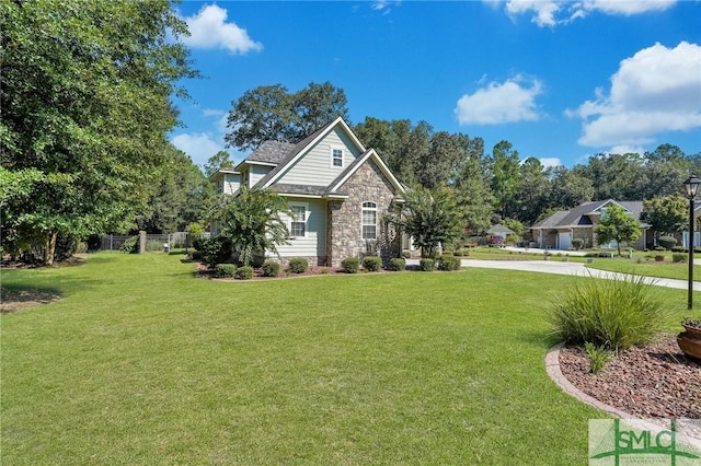 view of front of home with stone siding, fence, and a front yard