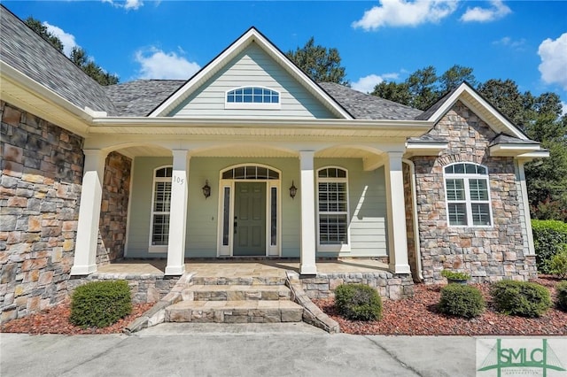 property entrance featuring stone siding, a porch, and a shingled roof