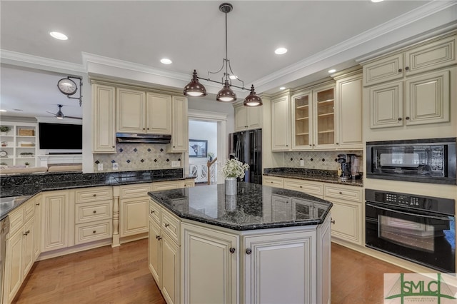 kitchen featuring cream cabinets, decorative light fixtures, black appliances, ceiling fan, and a kitchen island