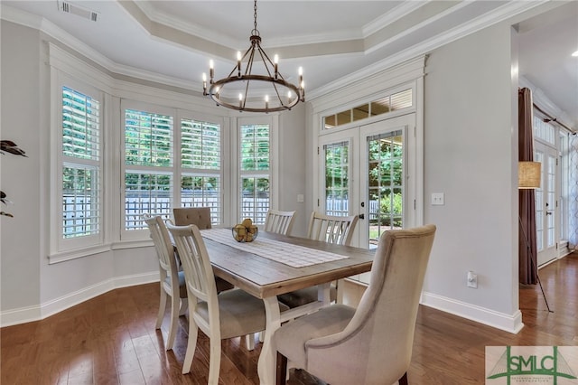 dining area featuring ornamental molding, dark hardwood / wood-style flooring, a healthy amount of sunlight, and an inviting chandelier