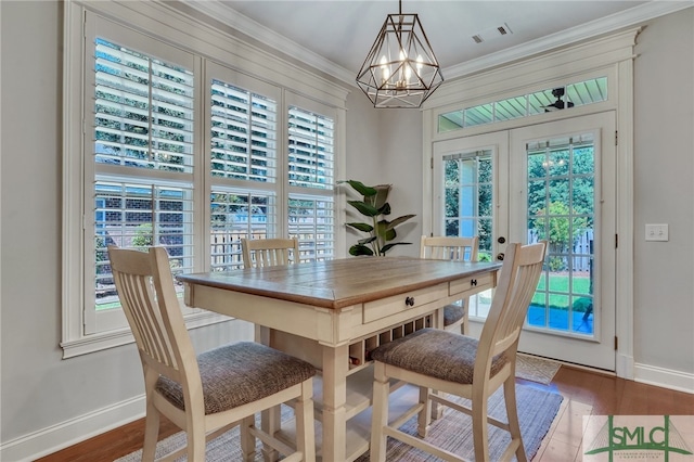 dining room featuring a healthy amount of sunlight, ornamental molding, hardwood / wood-style floors, and a chandelier