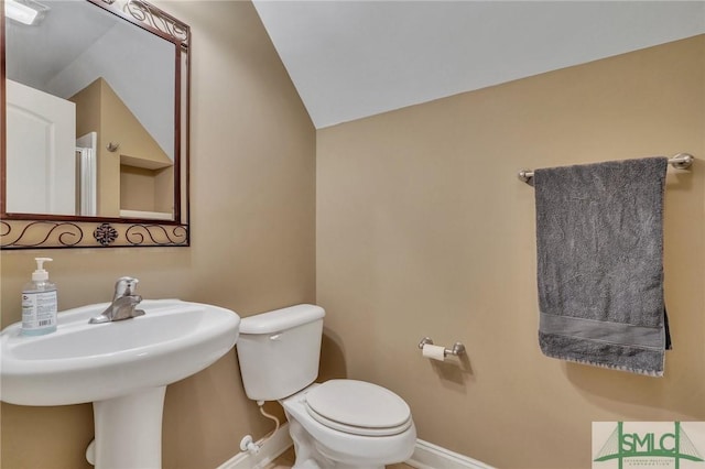 half bathroom with toilet, baseboards, and vaulted ceiling