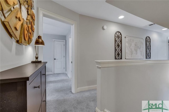 hallway with visible vents, baseboards, light colored carpet, an upstairs landing, and recessed lighting