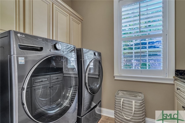 laundry room featuring washing machine and dryer, cabinets, and light tile patterned flooring