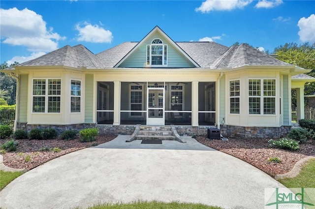 back of house with a shingled roof and a sunroom