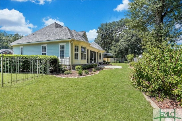 view of property exterior featuring a shingled roof, a lawn, and a fenced backyard