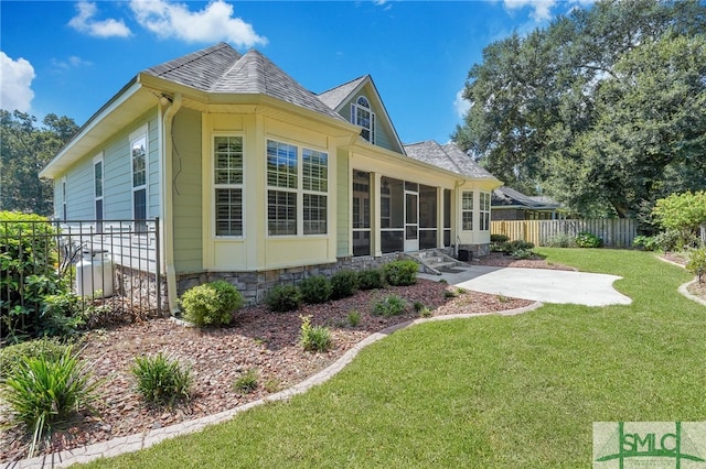 rear view of house featuring a yard and a sunroom