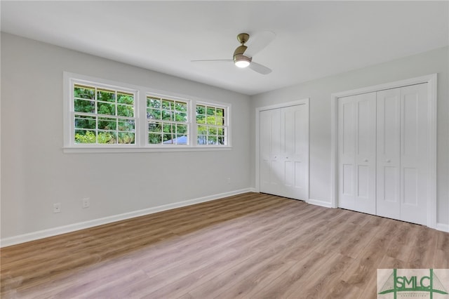 unfurnished bedroom with hardwood / wood-style floors, two closets, and ceiling fan