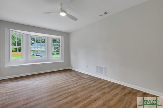 empty room with ceiling fan, hardwood / wood-style flooring, and a healthy amount of sunlight