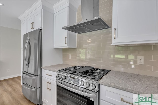 kitchen featuring appliances with stainless steel finishes, decorative backsplash, wall chimney exhaust hood, and light hardwood / wood-style flooring