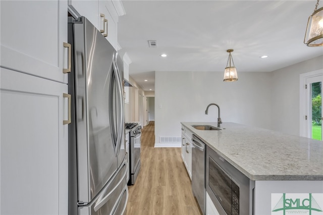 kitchen featuring light hardwood / wood-style floors, an island with sink, stainless steel appliances, sink, and white cabinets