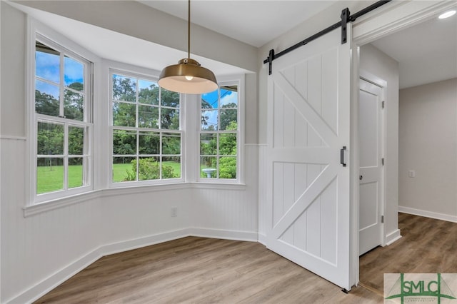 unfurnished dining area with wood-type flooring and a barn door