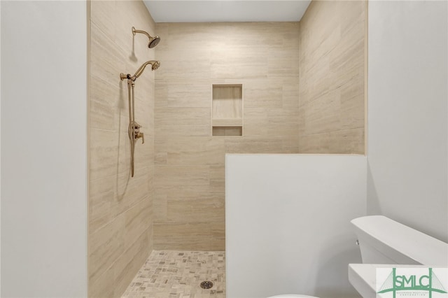 bathroom featuring tiled shower and toilet