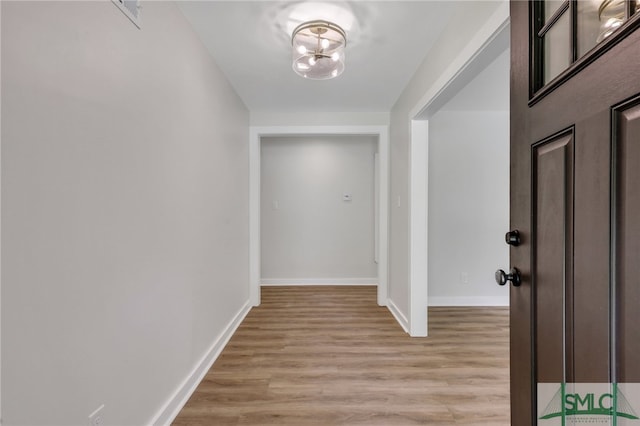 hall with a notable chandelier and light hardwood / wood-style floors