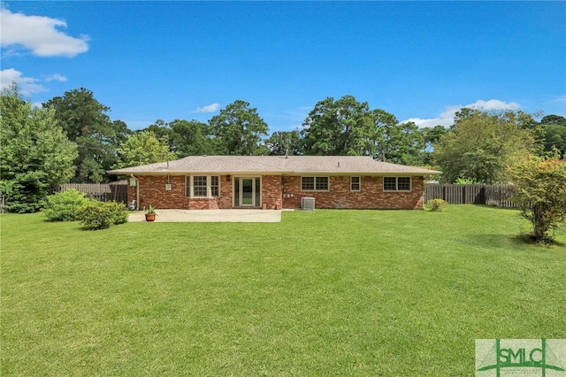 rear view of property with central AC unit, a patio area, and a lawn