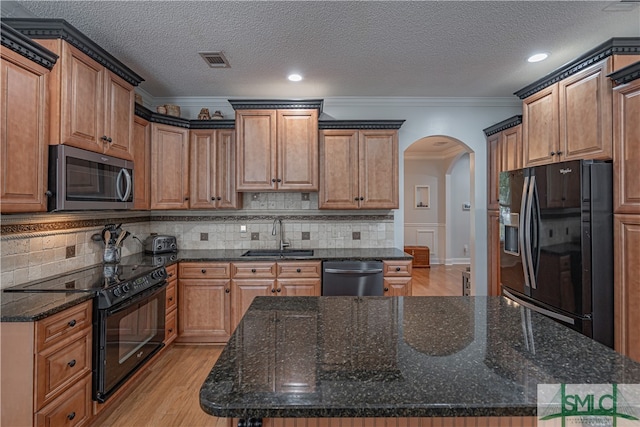 kitchen with black appliances, light hardwood / wood-style flooring, sink, decorative backsplash, and dark stone counters