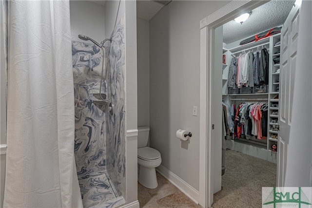 bathroom featuring a textured ceiling, toilet, and walk in shower