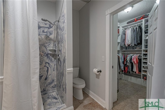 bathroom featuring a textured ceiling, a stall shower, a walk in closet, and toilet