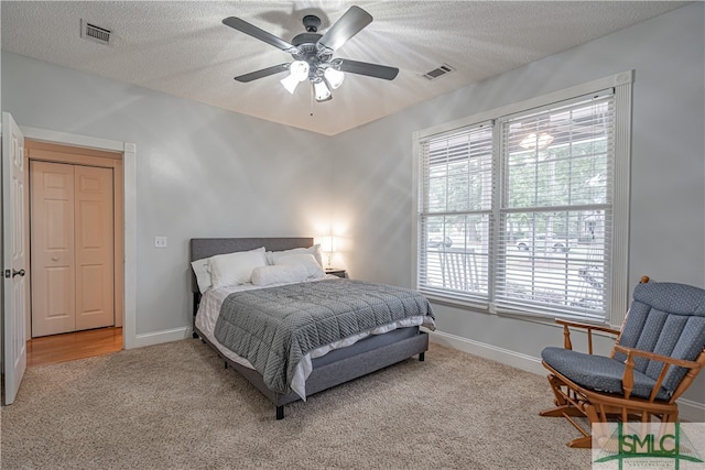 carpeted bedroom featuring ceiling fan and a textured ceiling